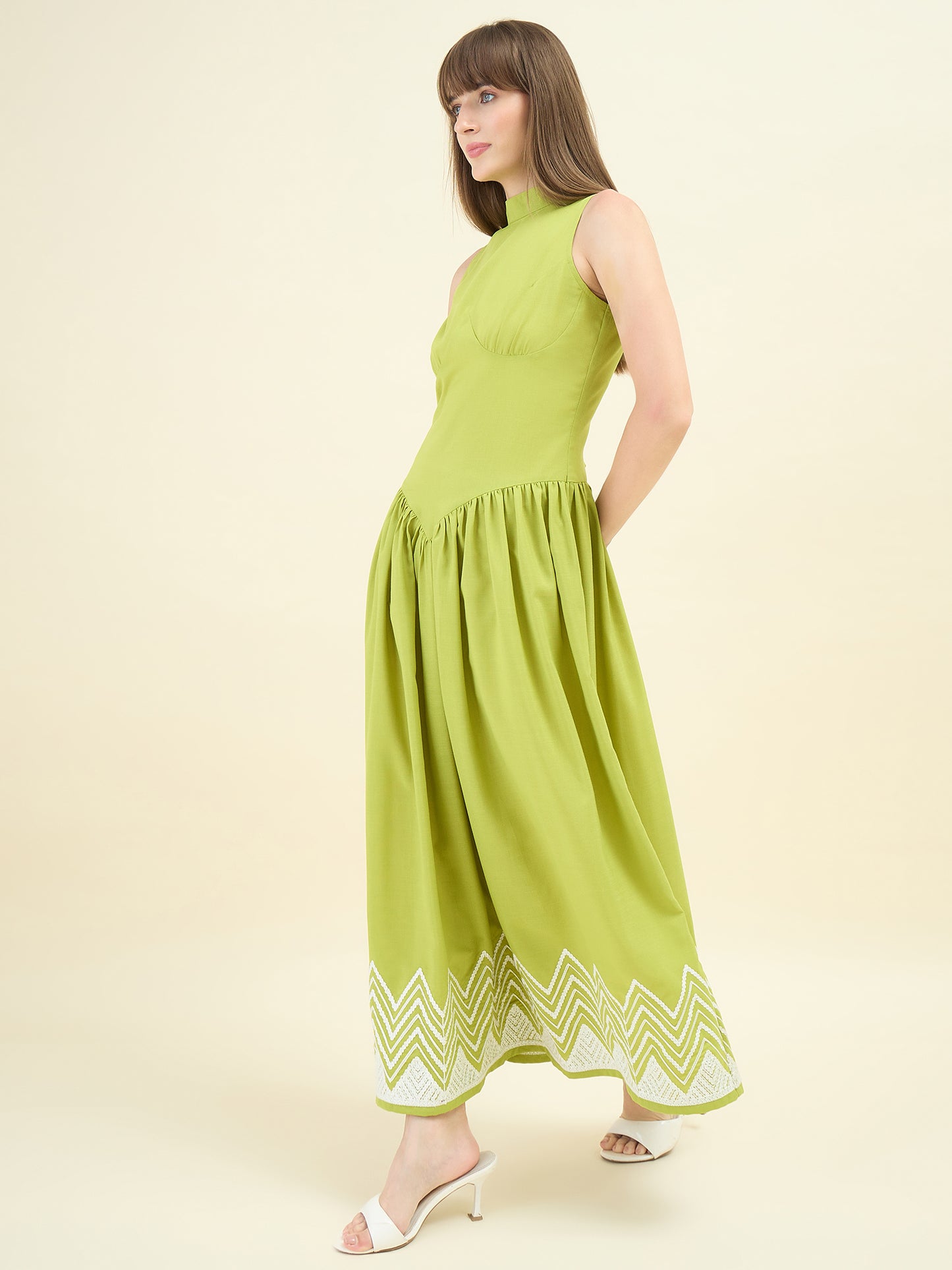 Woman wearing a green dress with zigzag pattern on a beige background