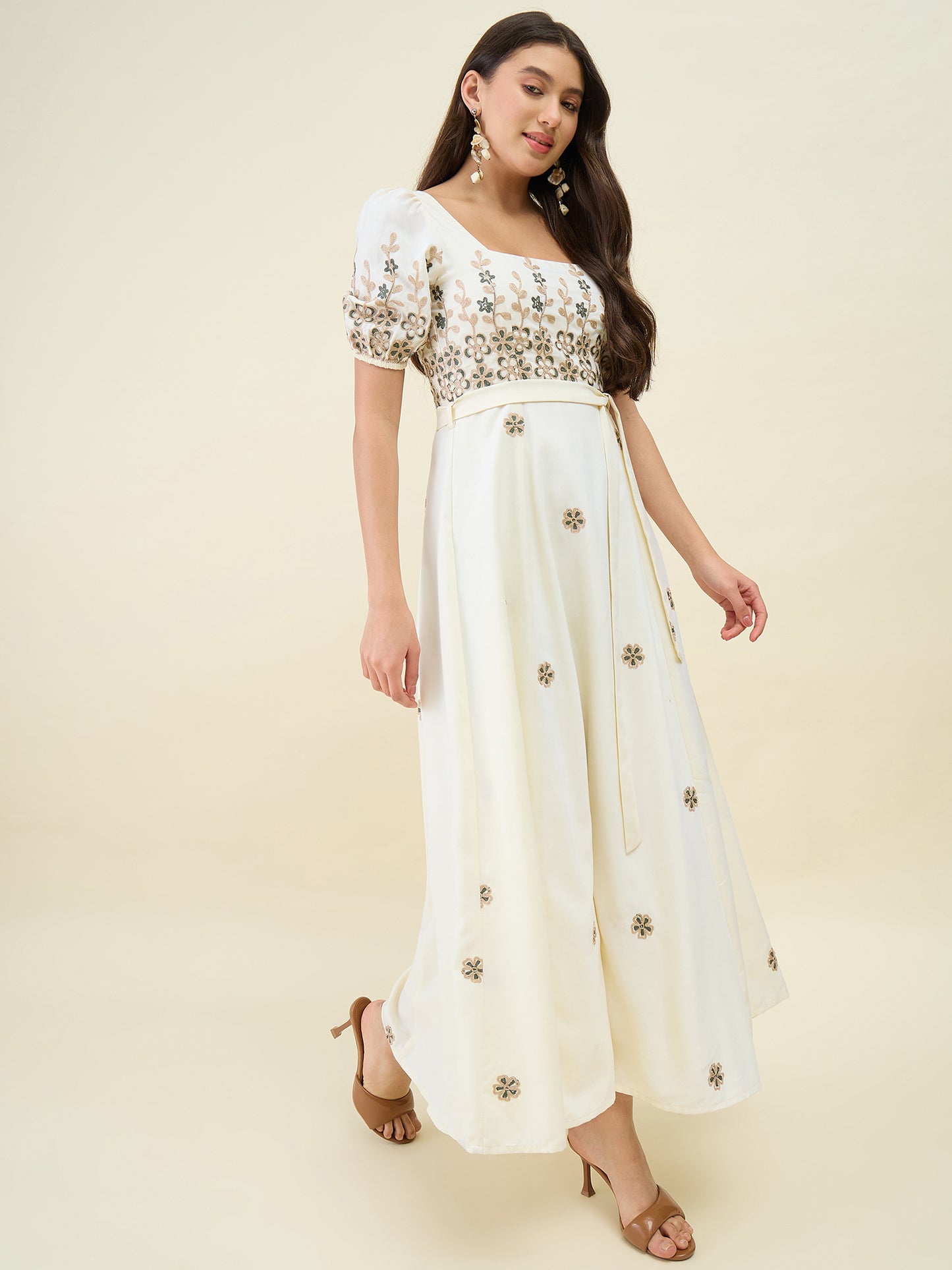 Woman wearing a white dress with floral embroidery on a beige background