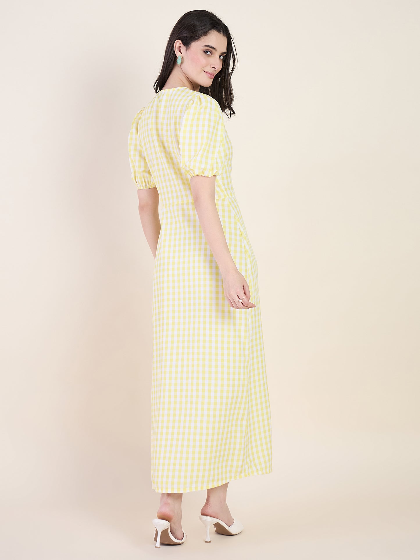 Woman wearing a yellow checkered dress on a beige background