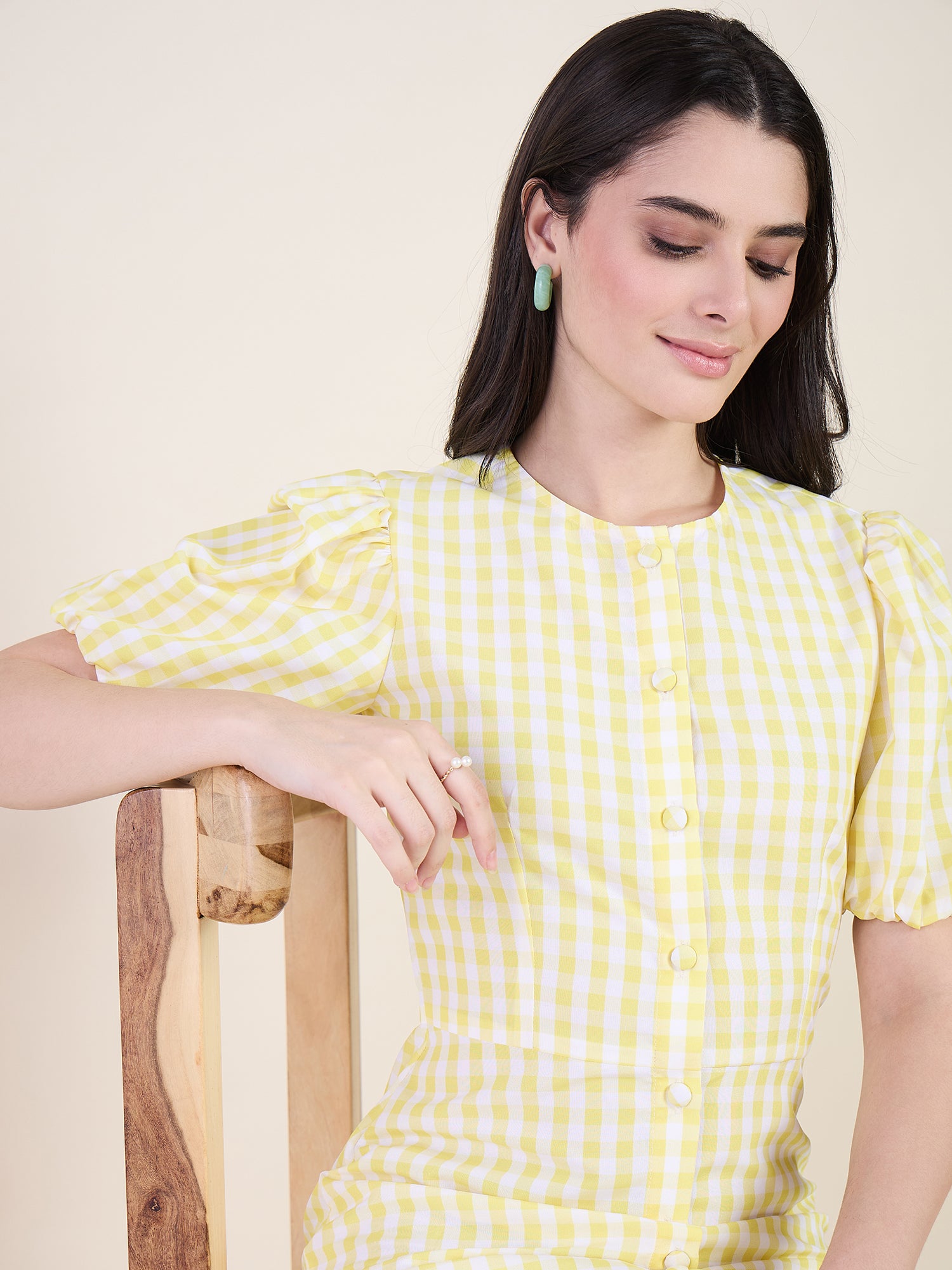 Woman wearing a yellow checkered dress on a beige background
