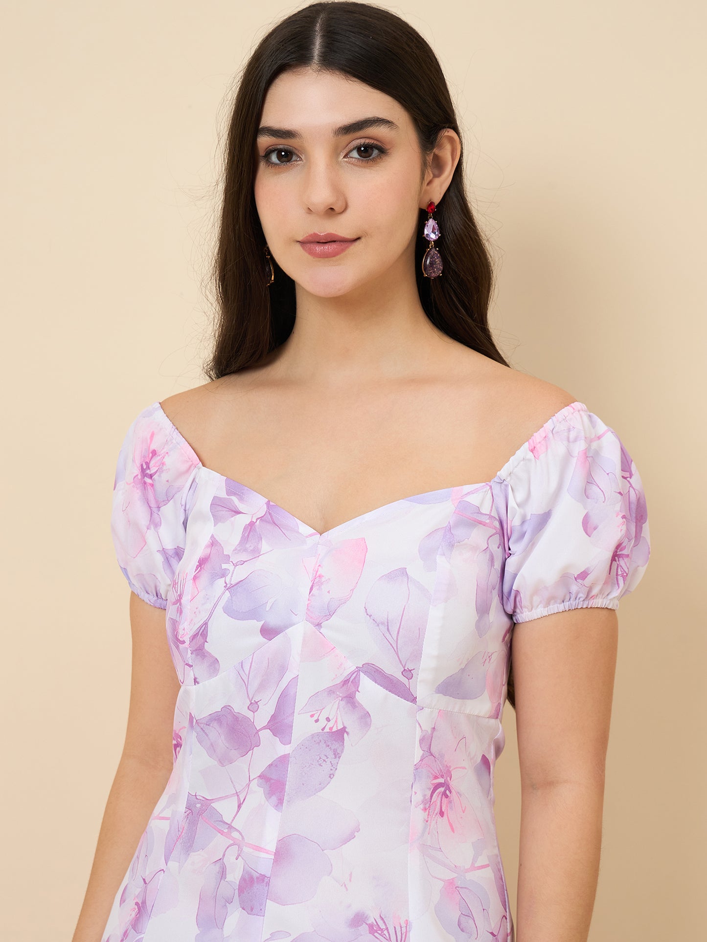Woman wearing a floral off-shoulder top against a beige background