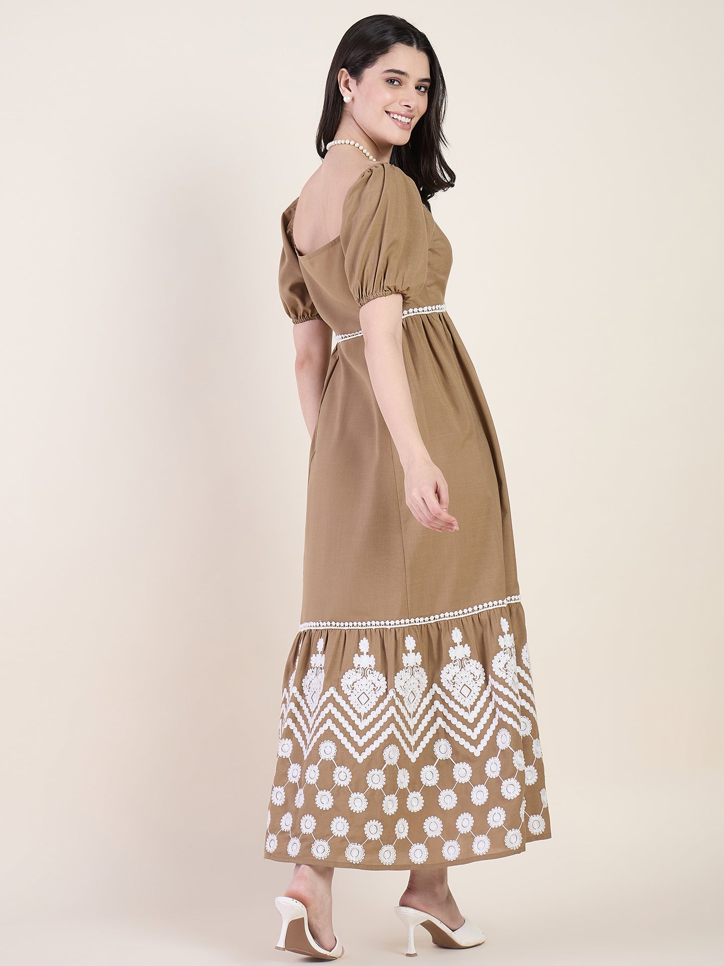 Woman wearing a brown dress with white patterns on a beige background