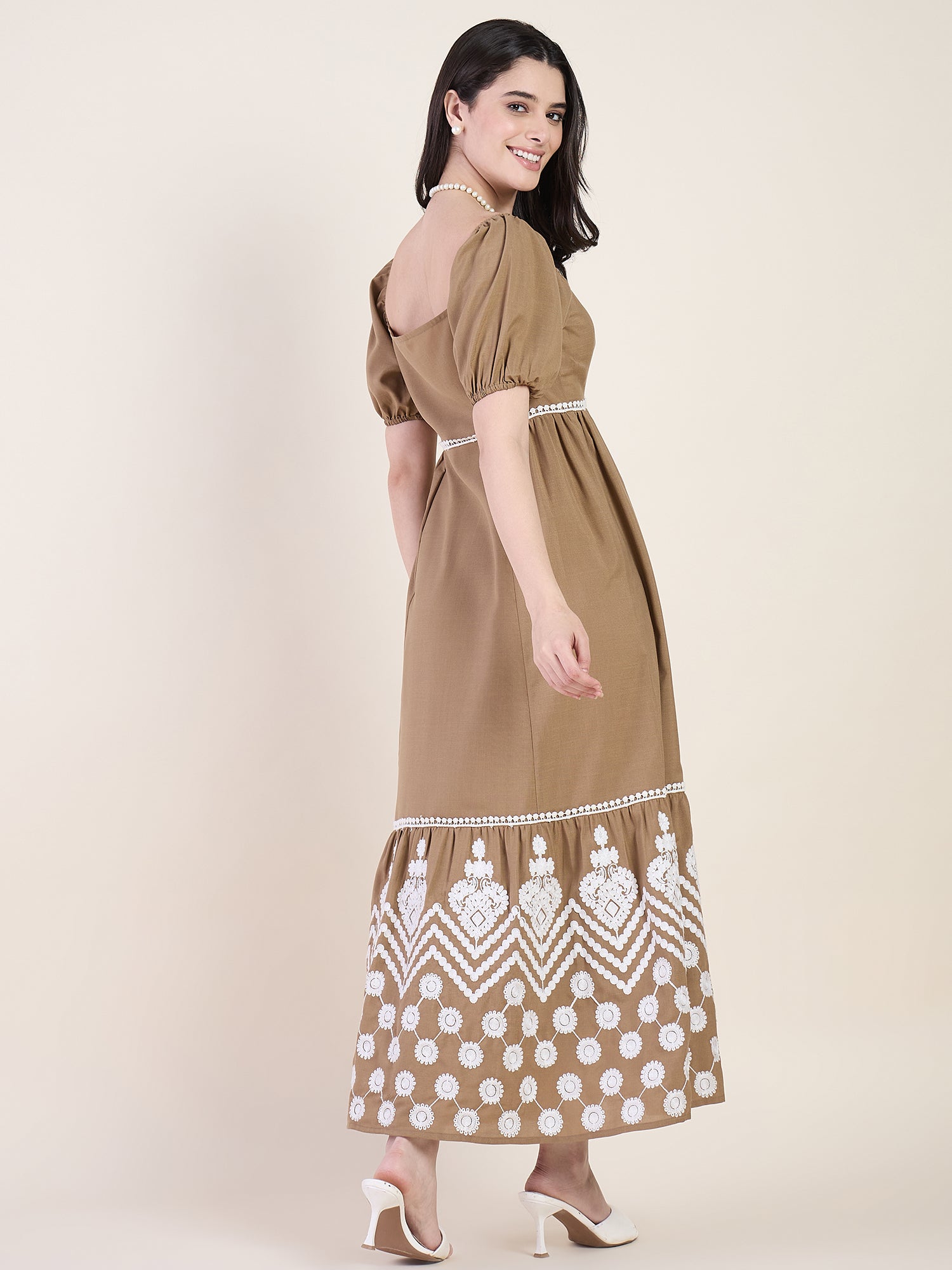 Woman wearing a brown dress with white patterns on a beige background