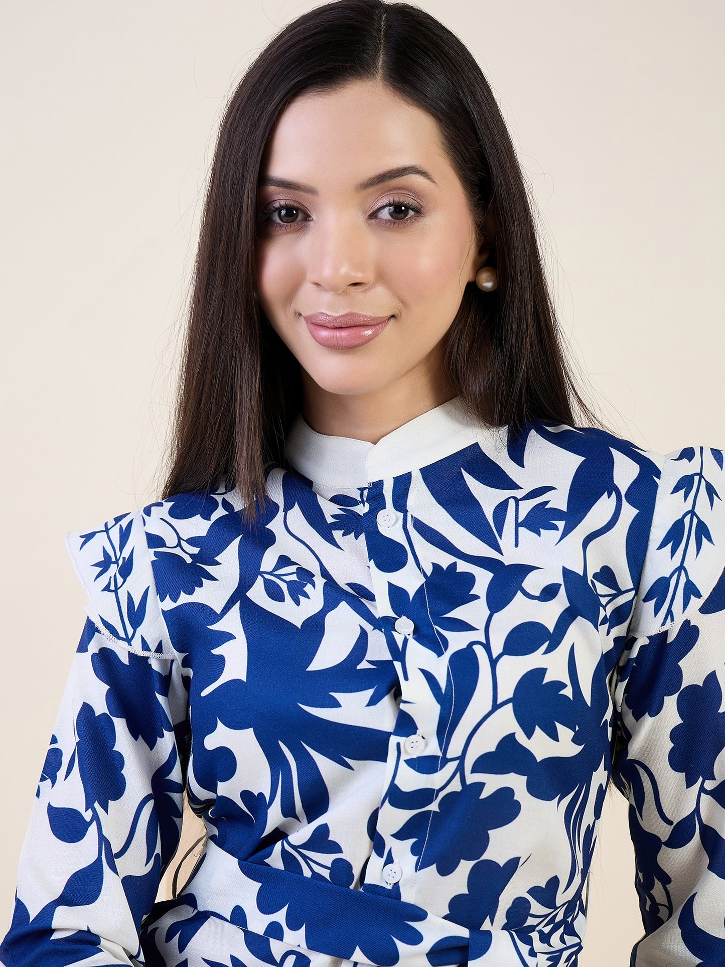 Woman wearing a blue and white floral blouse against a beige background