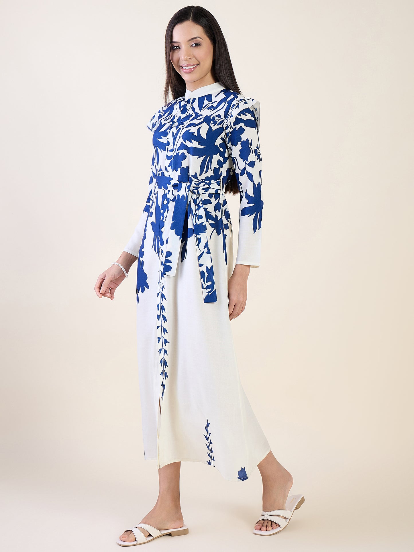 Woman wearing a white dress with blue floral patterns on a plain background