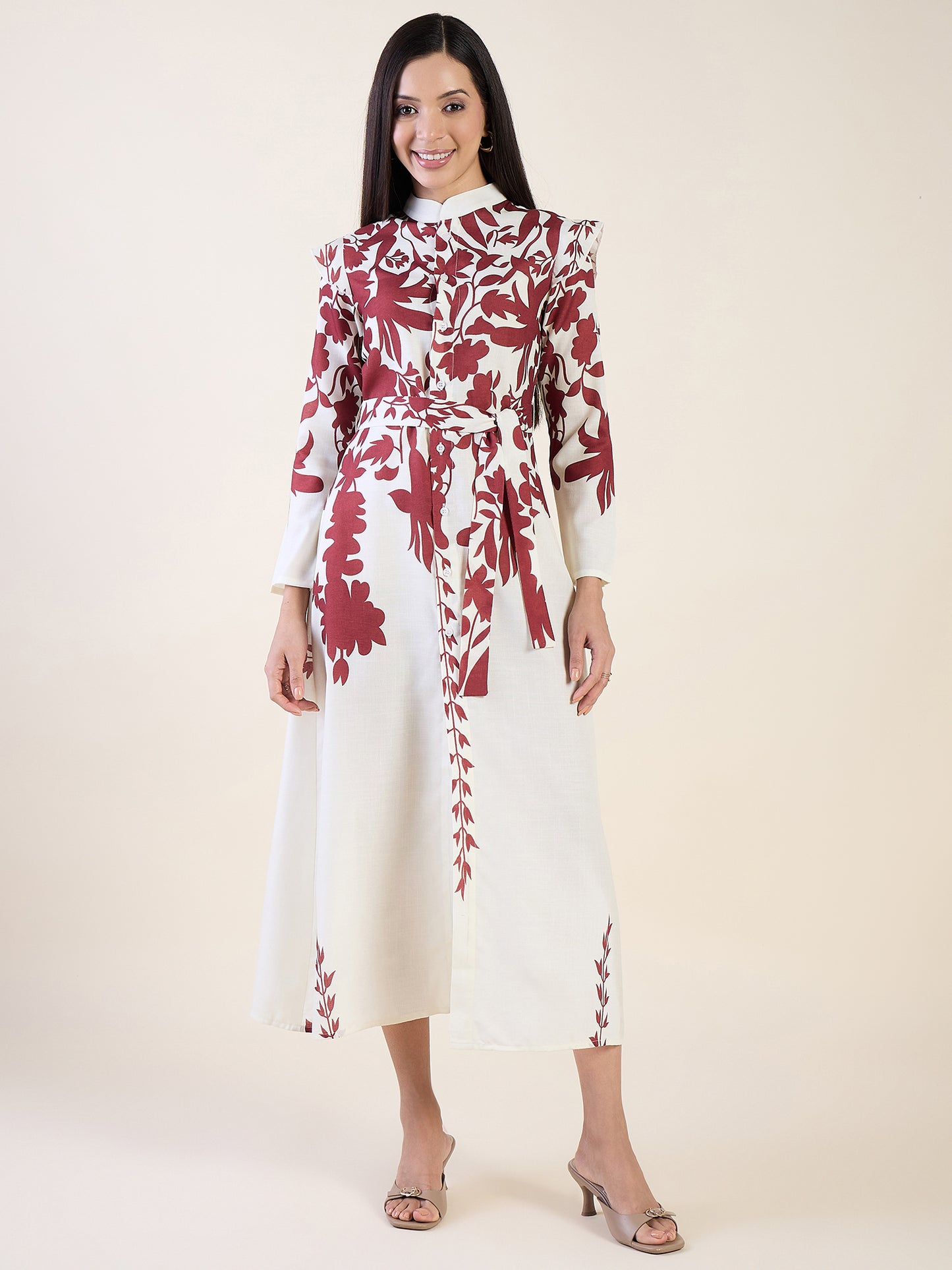 Woman wearing a white dress with red floral patterns on a plain background
