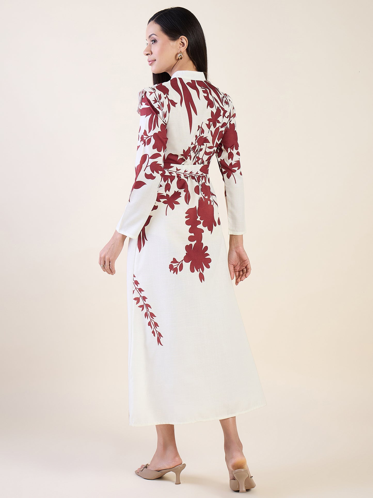 Woman wearing a white dress with red floral patterns on a plain background