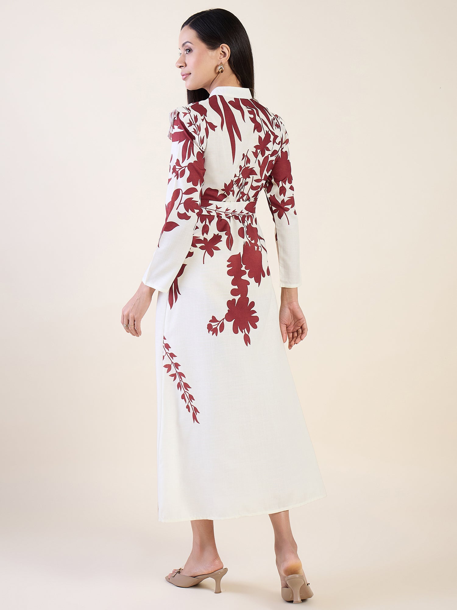 Woman wearing a white dress with red floral patterns on a plain background