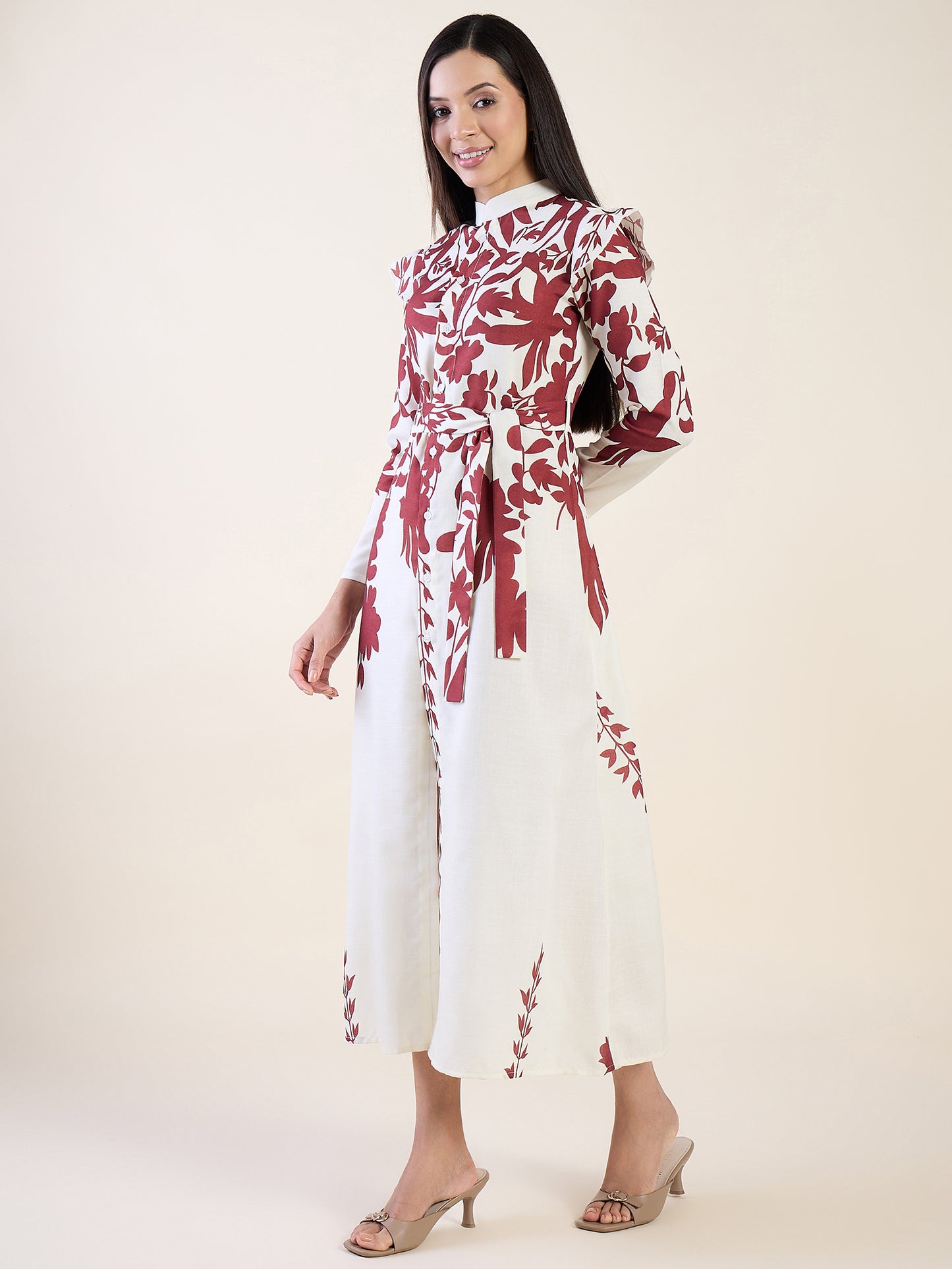 Woman wearing a white dress with red floral patterns on a plain background