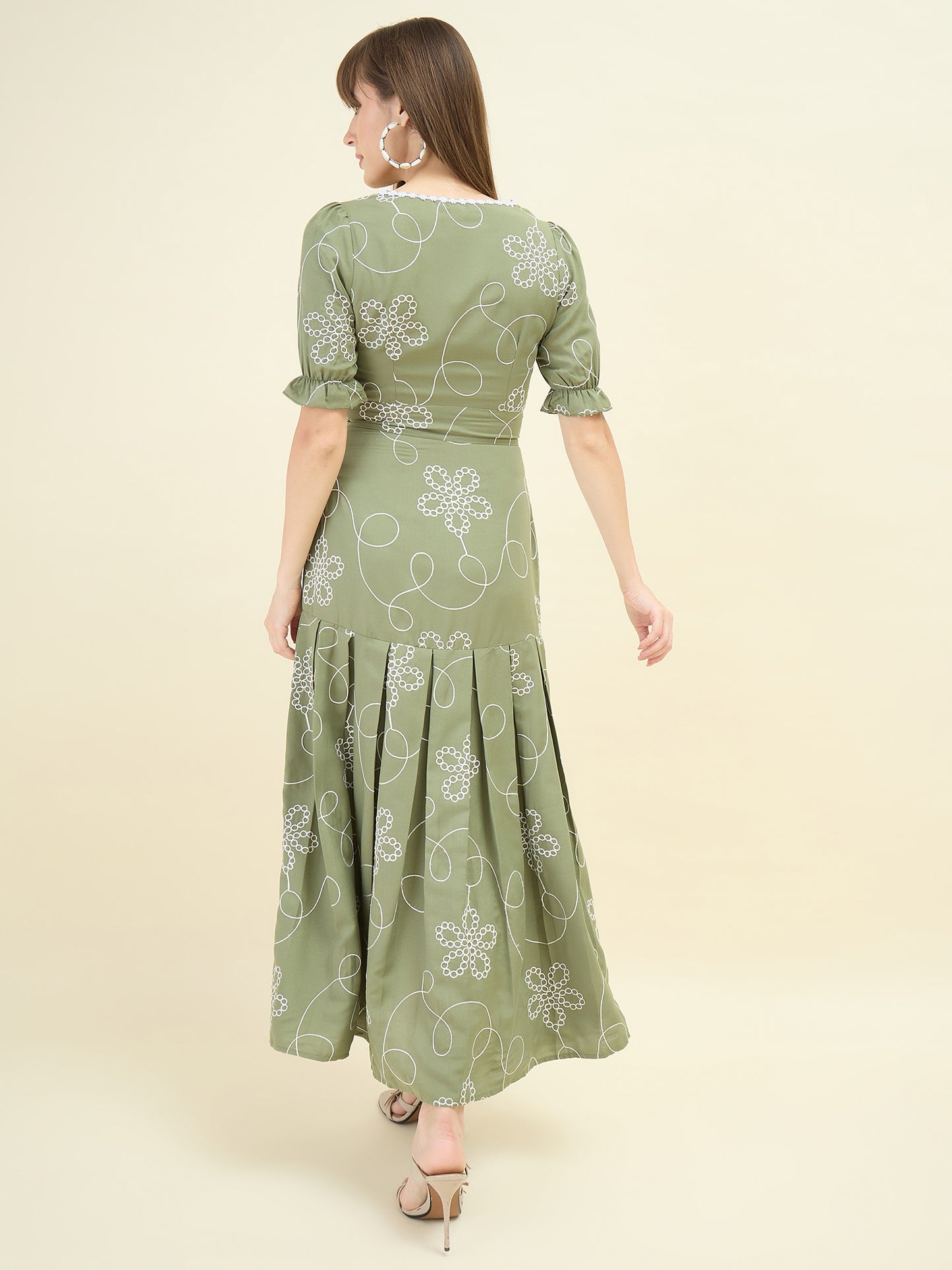Woman wearing a green dress with floral patterns on a beige background