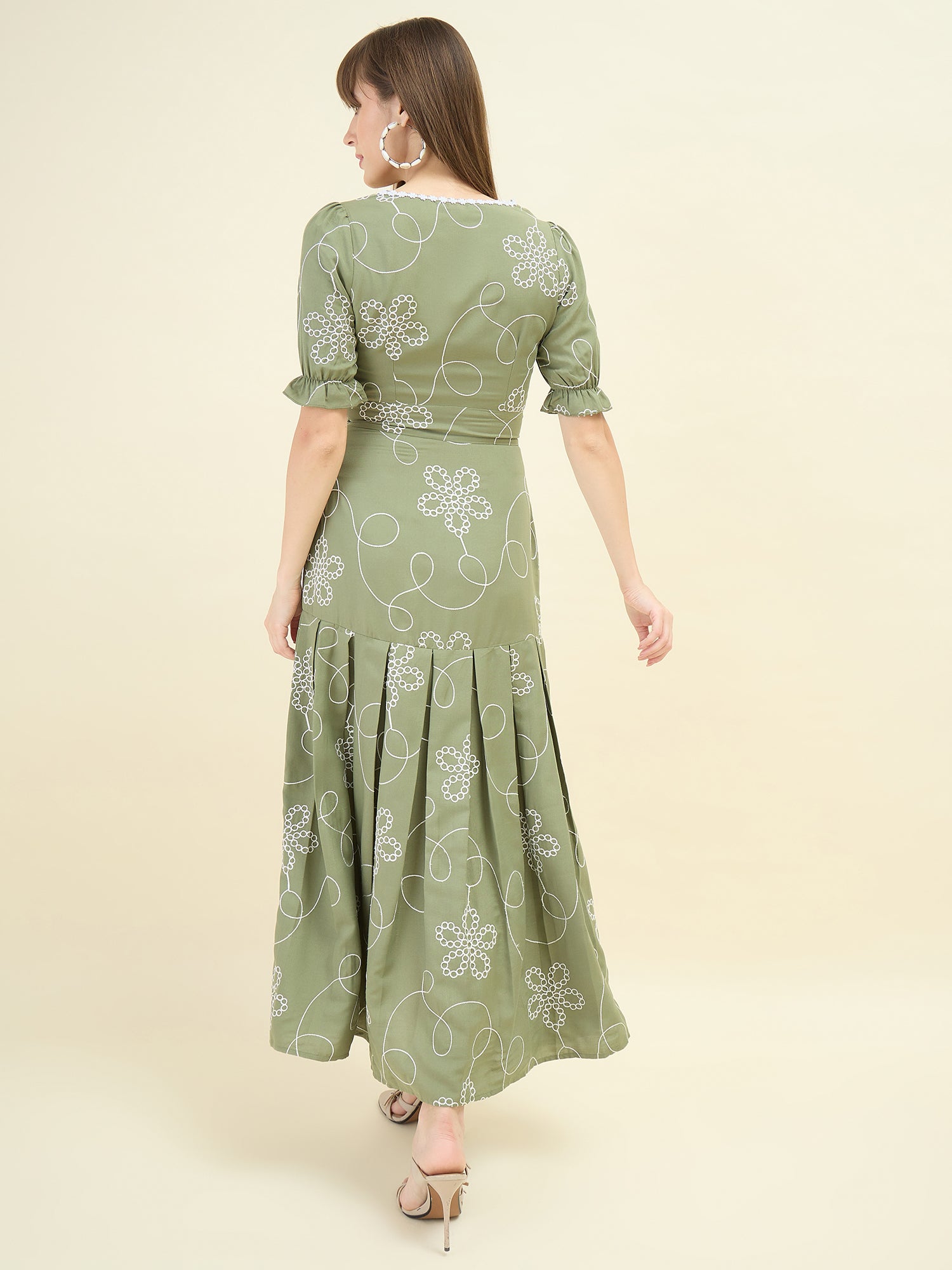 Woman wearing a green dress with floral patterns on a beige background