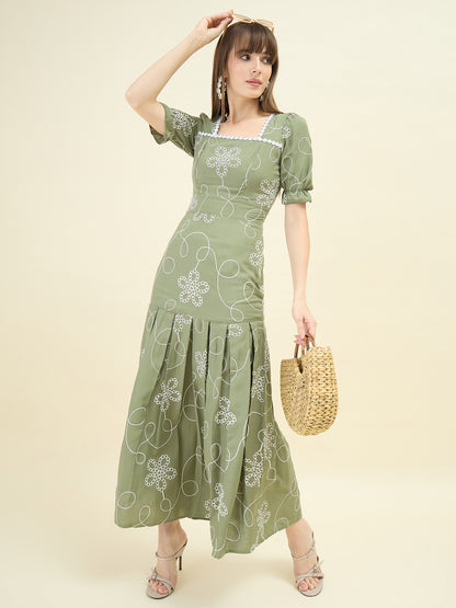 Woman wearing a green dress with floral patterns on a beige background
