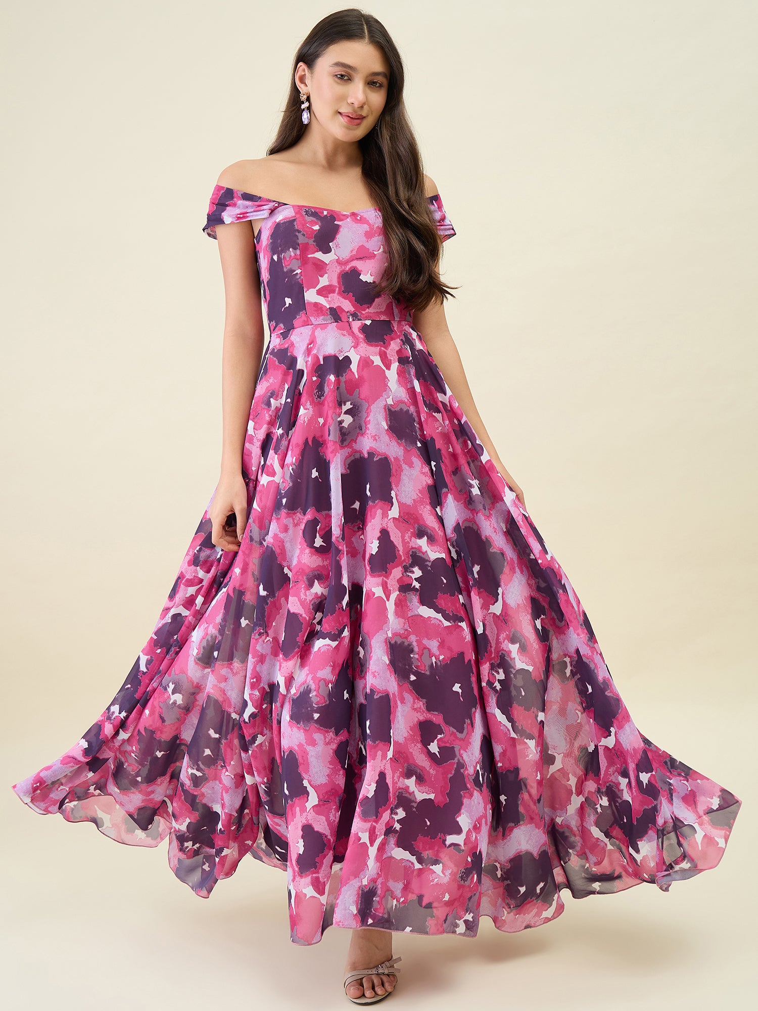 Woman wearing a pink and purple floral off-shoulder dress on a beige background