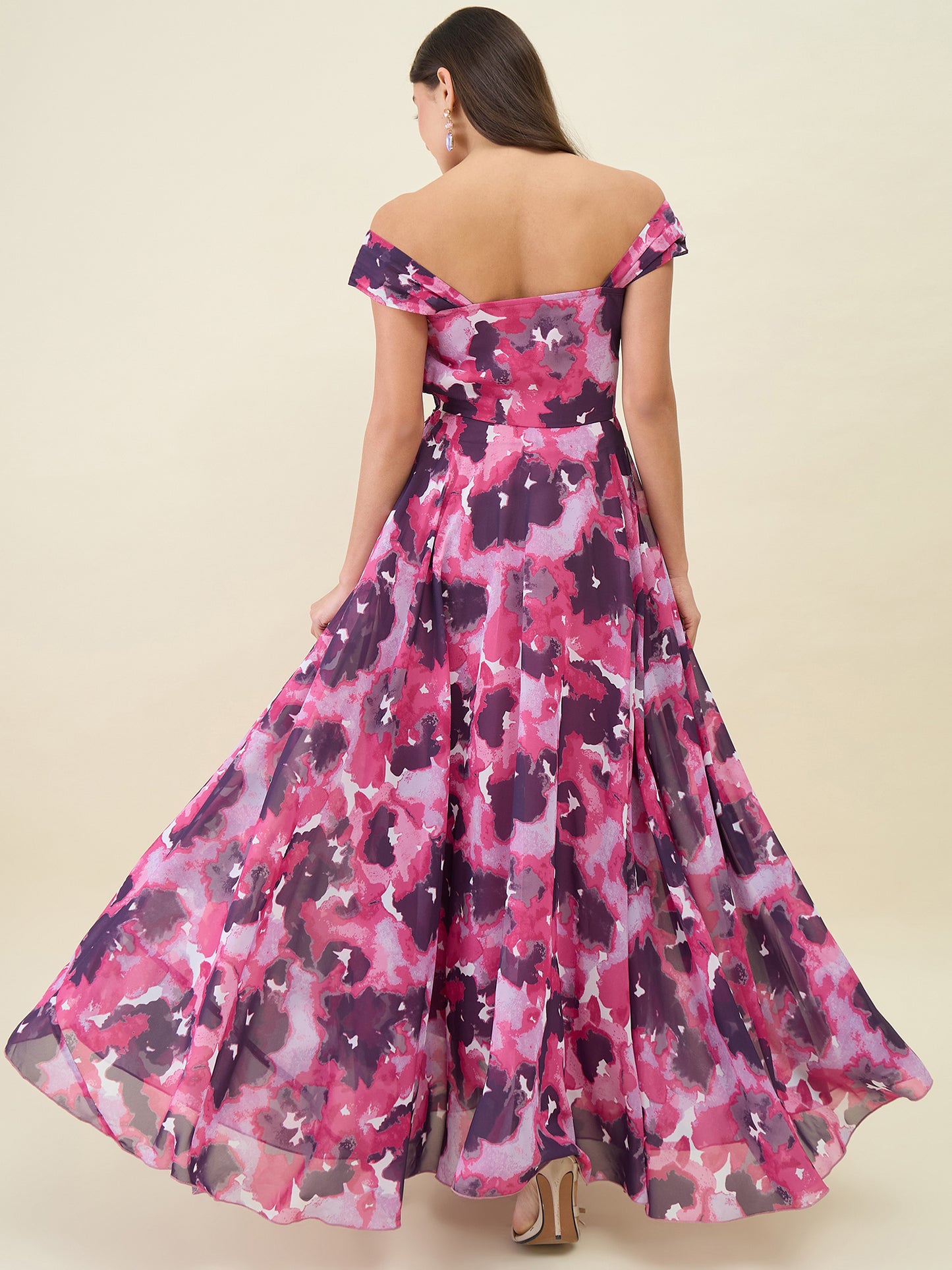 Woman wearing a pink and purple floral off-shoulder dress on a beige background