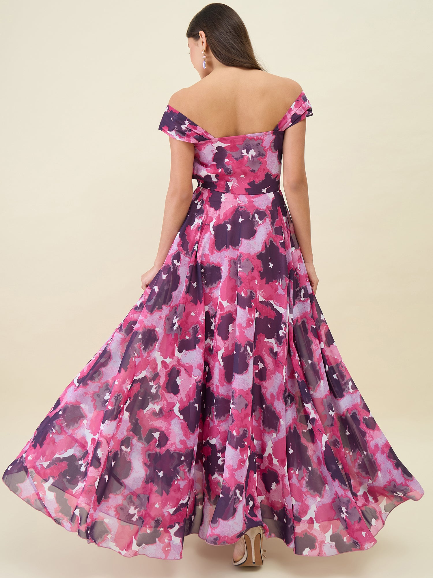 Woman wearing a pink and purple floral off-shoulder dress on a beige background