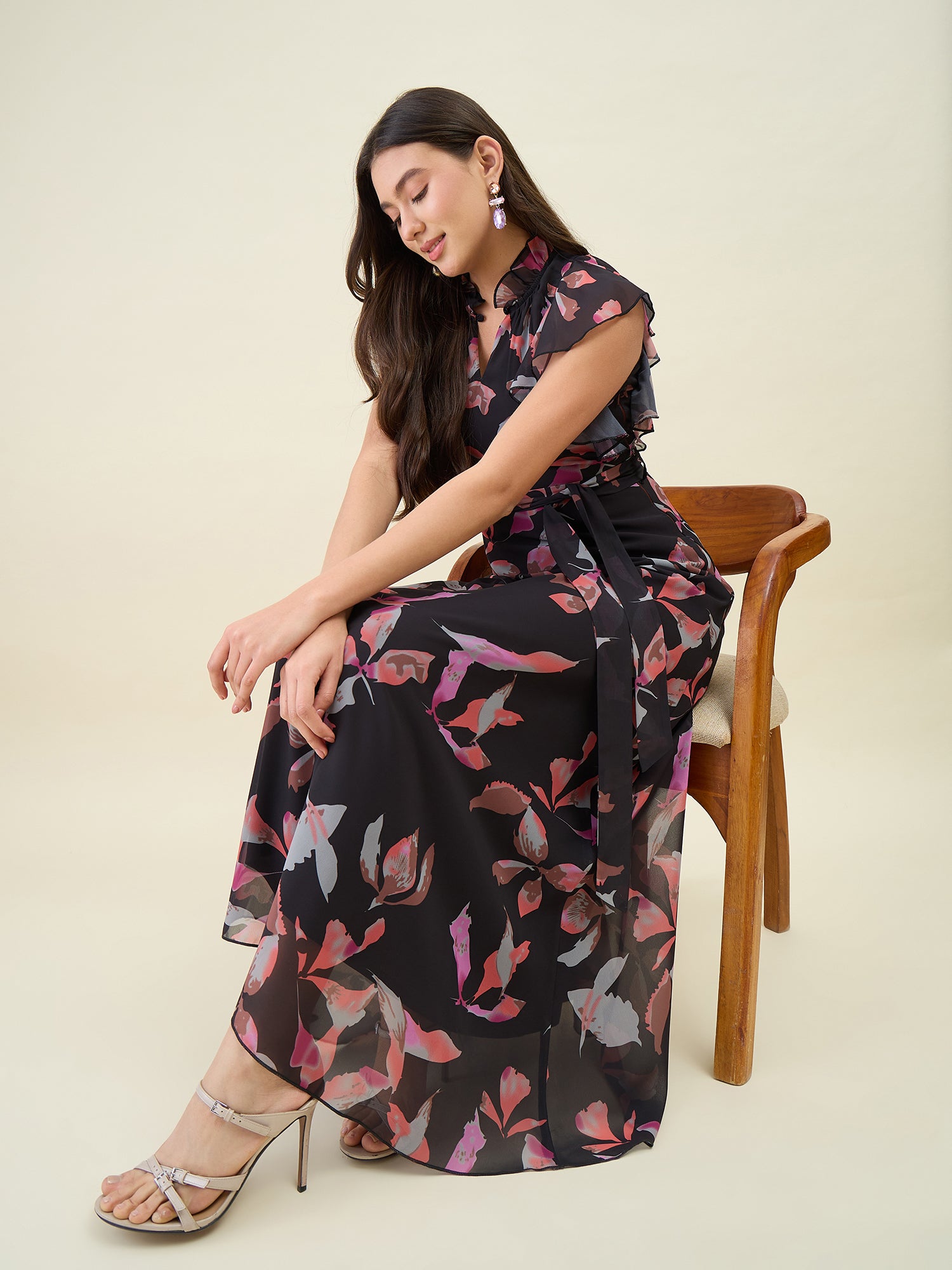 Woman sitting on a chair wearing a floral dress with a plain background