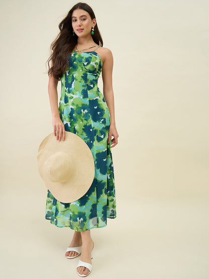 Woman wearing a green floral dress holding a straw hat on a beige background