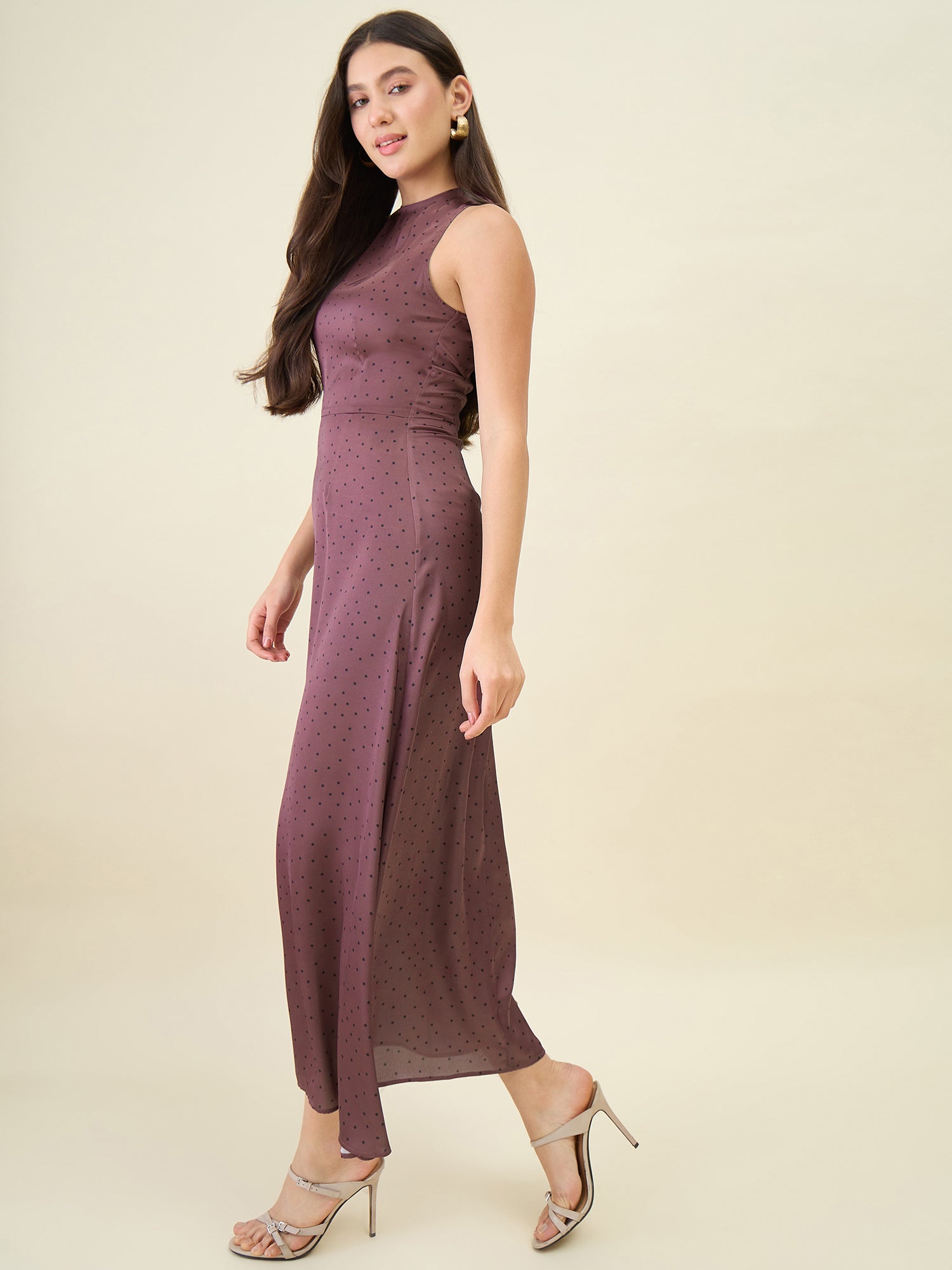 Woman wearing a sleeveless, long, brown dress on a beige background