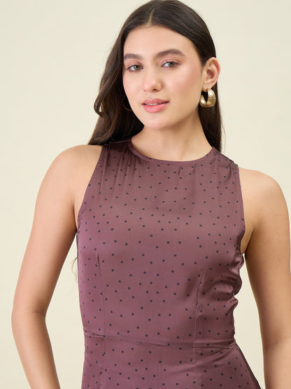 Woman wearing a sleeveless brown dress with black polka dots against a beige background