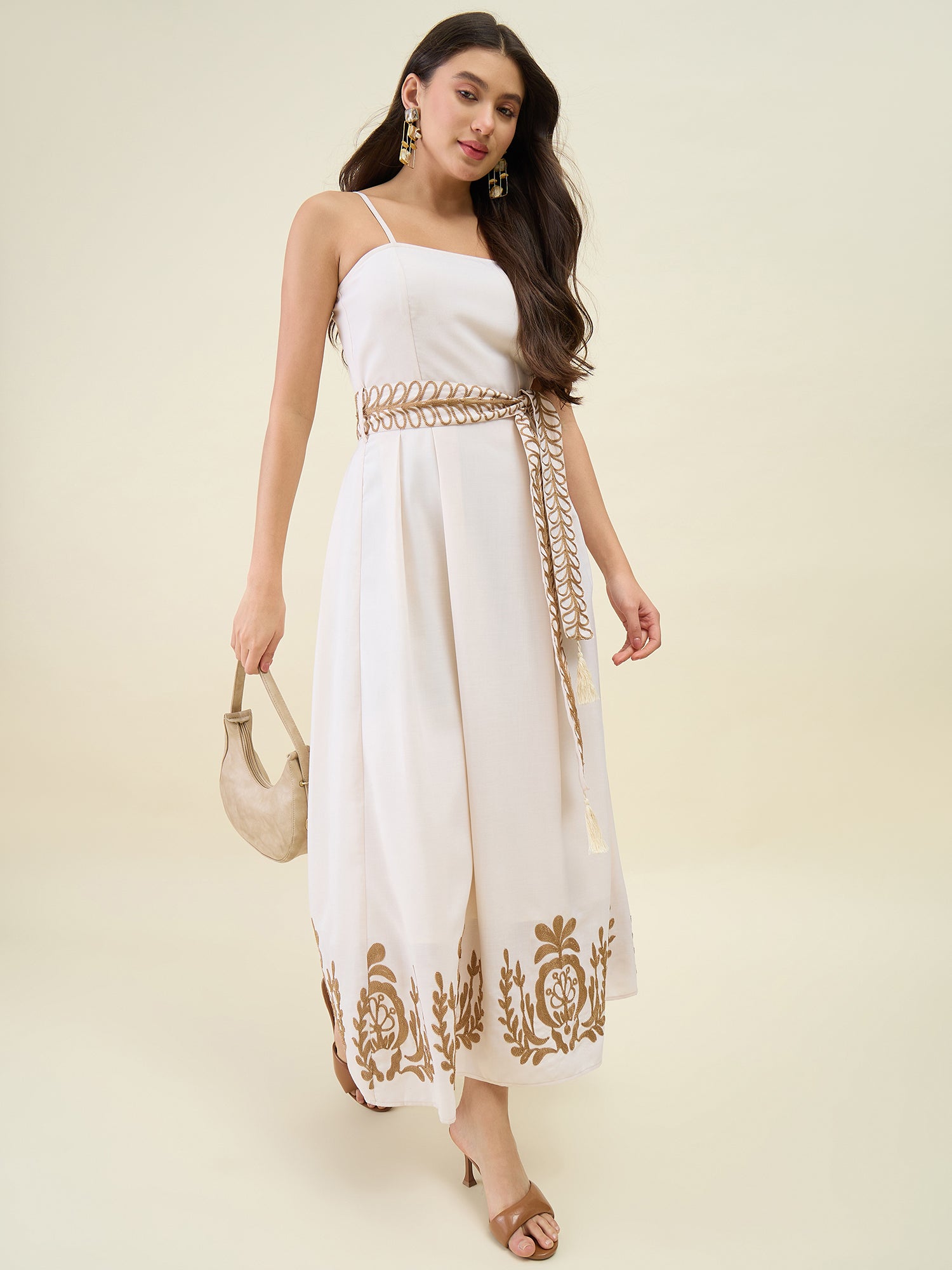 Woman wearing a white dress with gold embroidery on a beige background