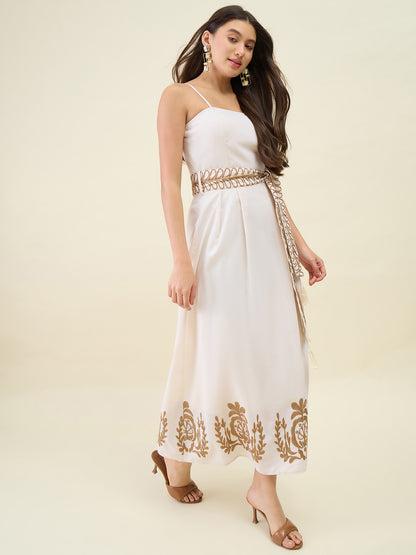 Woman wearing a white dress with gold embroidery on a beige background