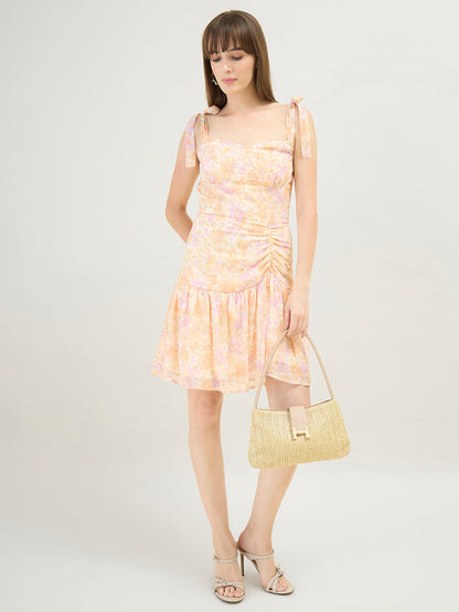 Woman wearing a light pink floral dress holding a matching handbag on a white background