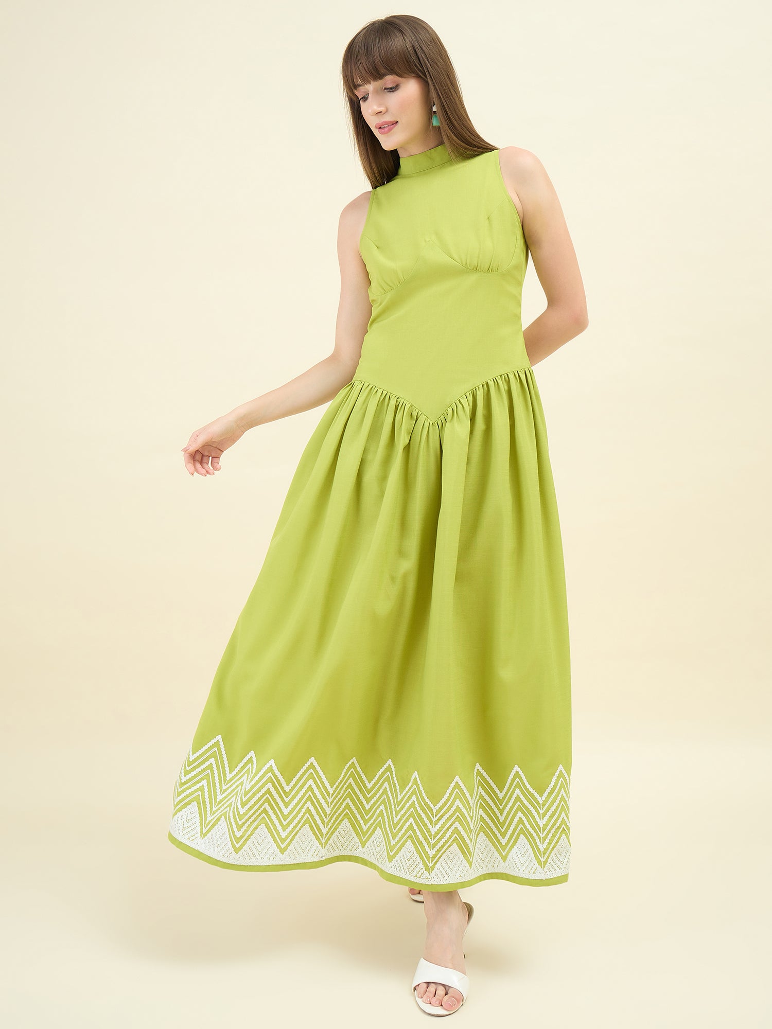 Woman wearing a green dress with white embroidery on a beige background