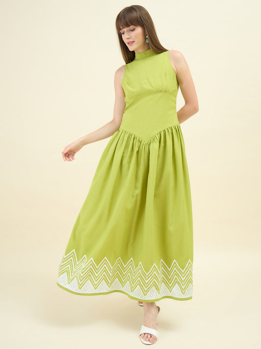 Woman wearing a green dress with white embroidery on a beige background