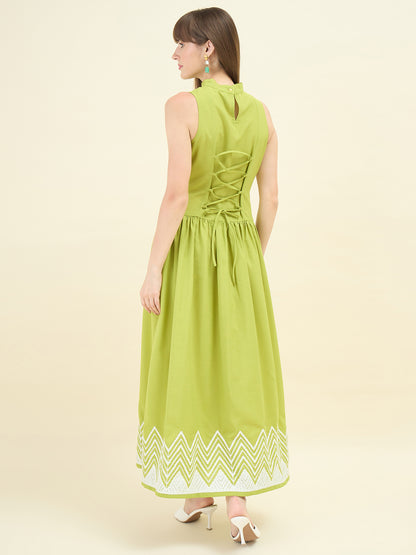 Woman wearing a sage green dress with a zigzag pattern on a beige background