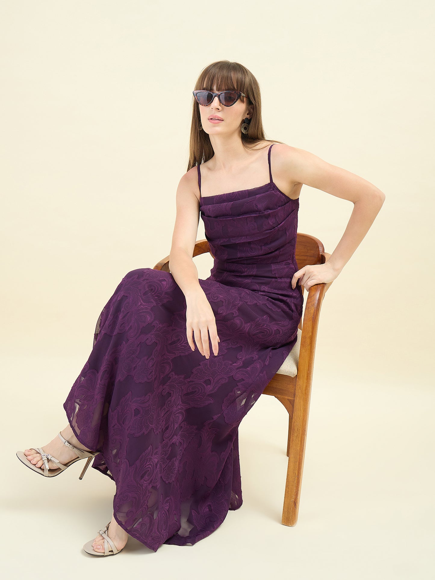 Woman wearing a purple dress sitting on a chair against a beige background