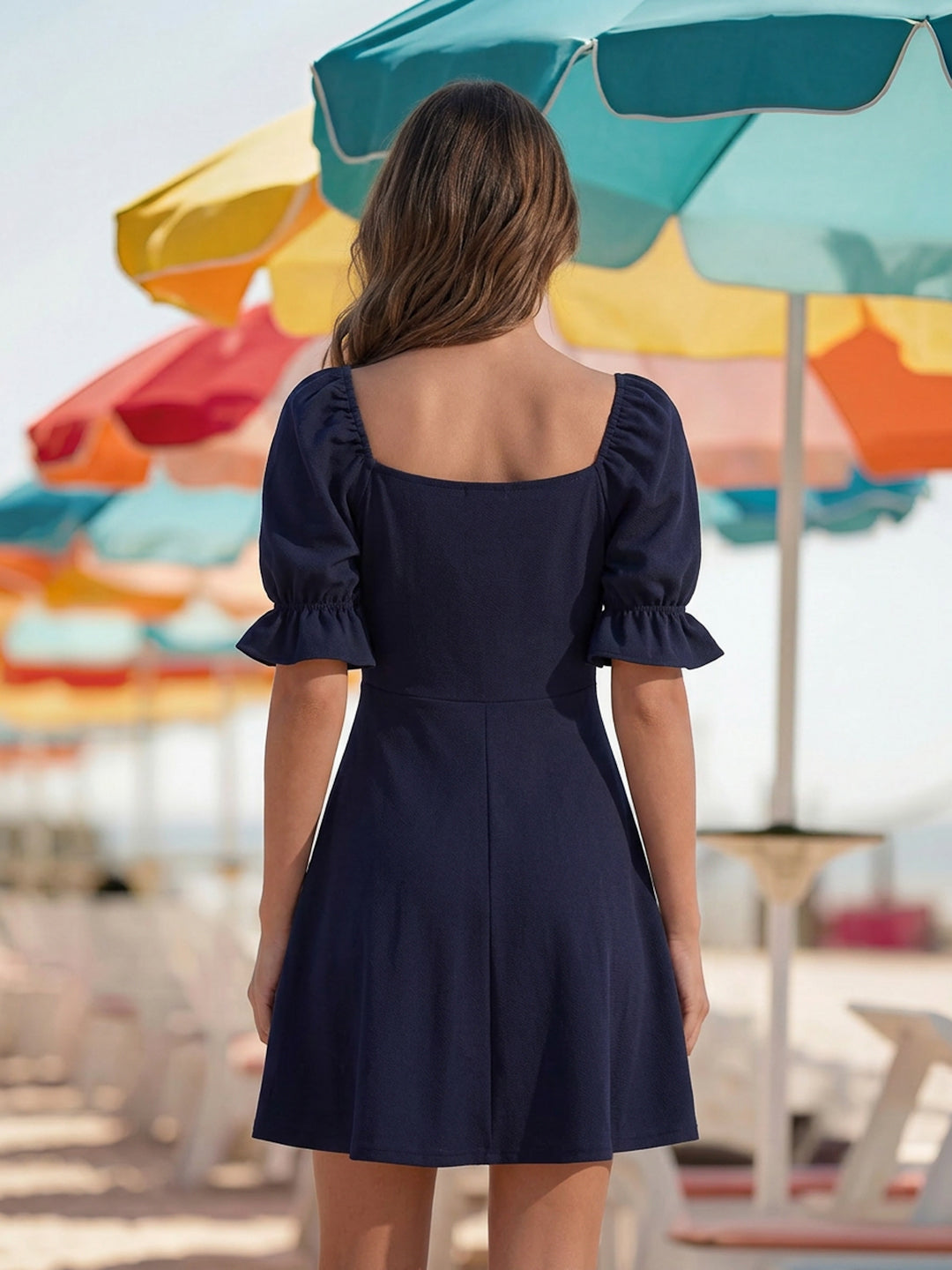 Woman in a navy dress standing under colorful beach umbrellas