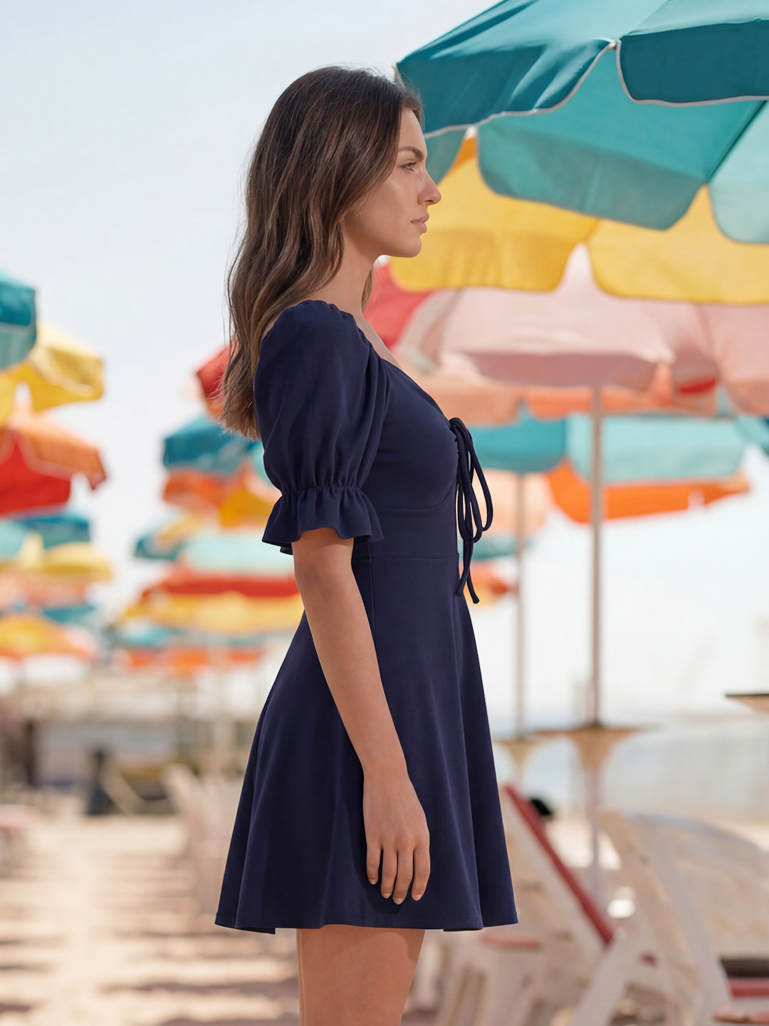 Woman in a navy dress standing under colorful beach umbrellas.