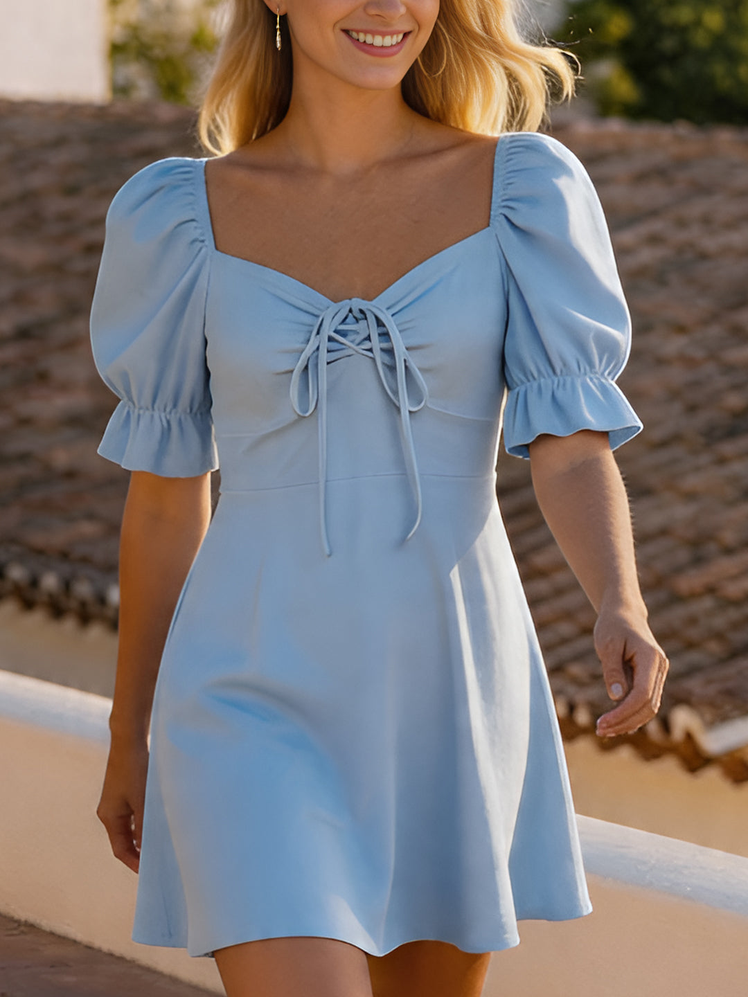 Woman wearing a light blue dress with puff sleeves against a blurred outdoor background