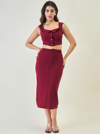 Woman wearing a maroon outfit with a top and skirt on a plain background