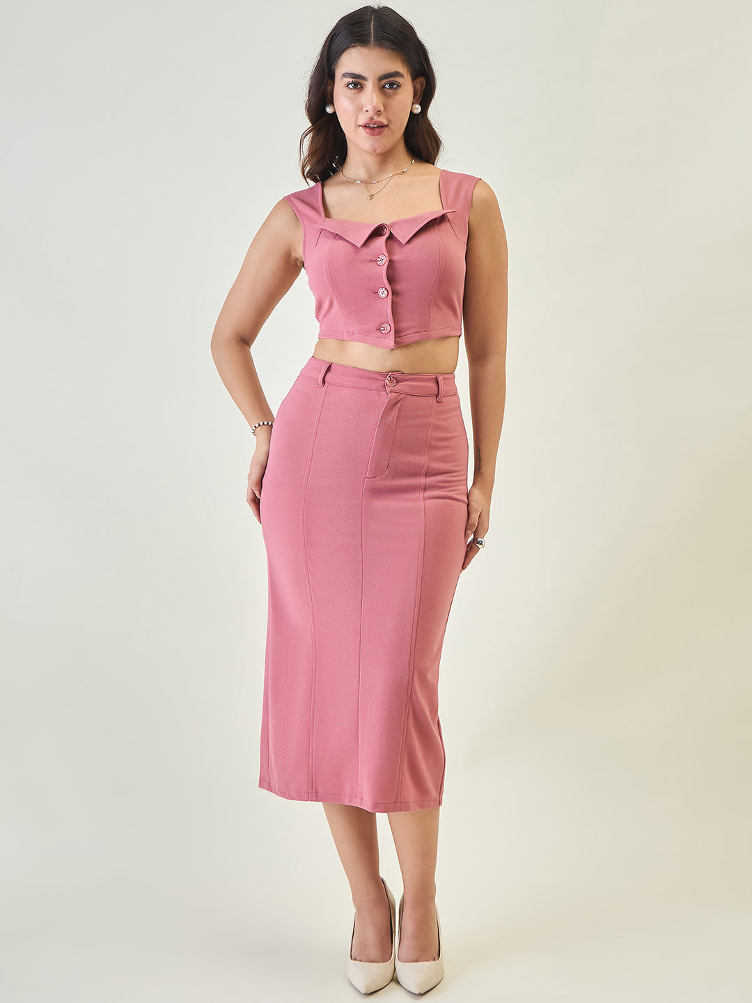 Woman wearing a pink outfit with a top and skirt on a white background