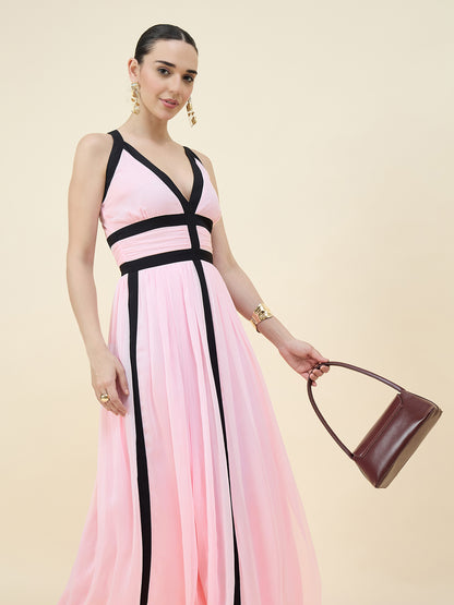 Woman wearing a pink and black dress holding a brown handbag on a beige background