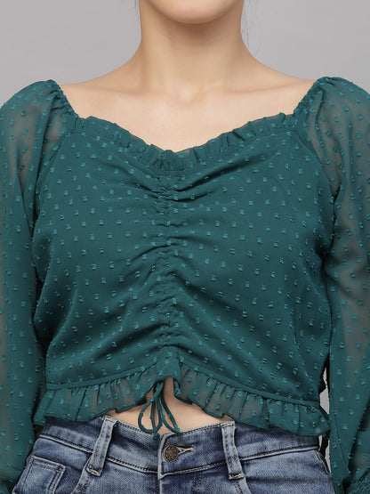 Green patterned top worn by a person on a gray background