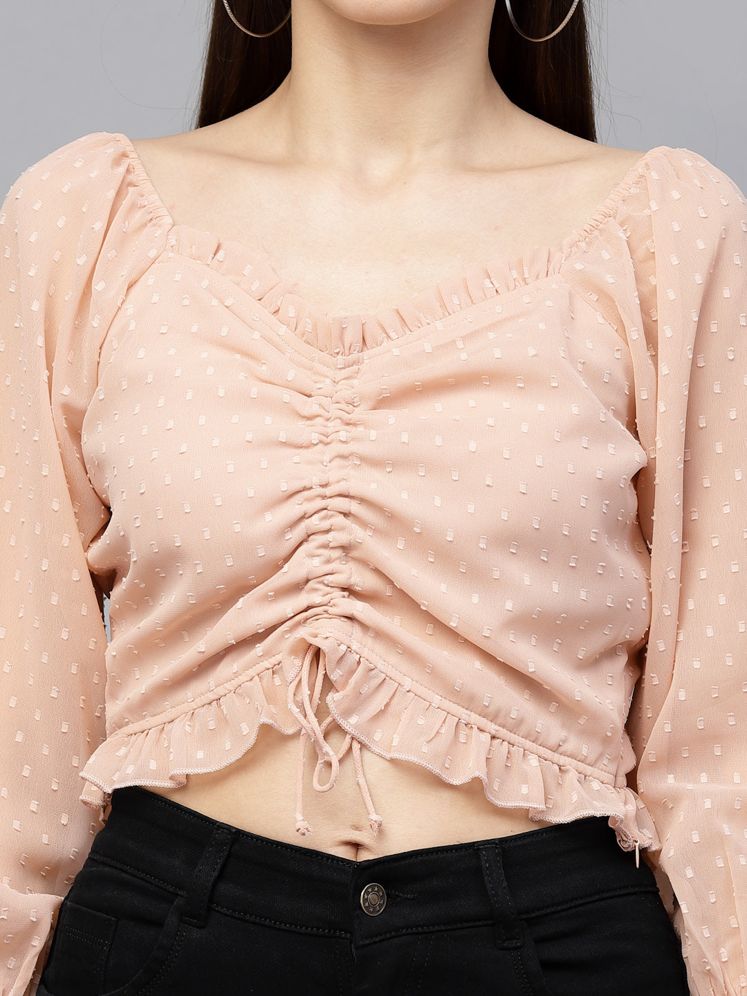 Peach polka dot top with ruched design on a gray background