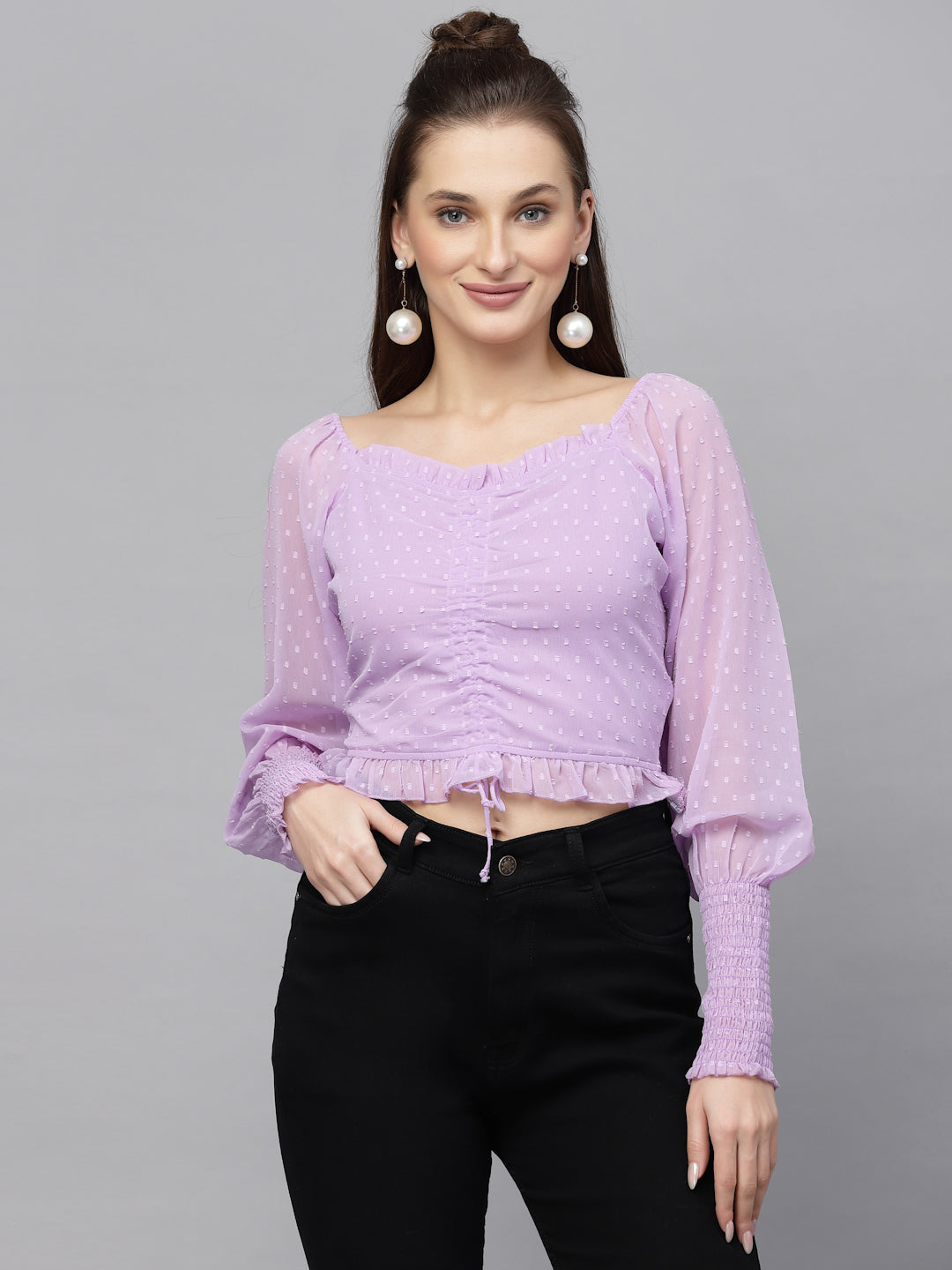 Woman wearing a purple top with long sleeves on a gray background