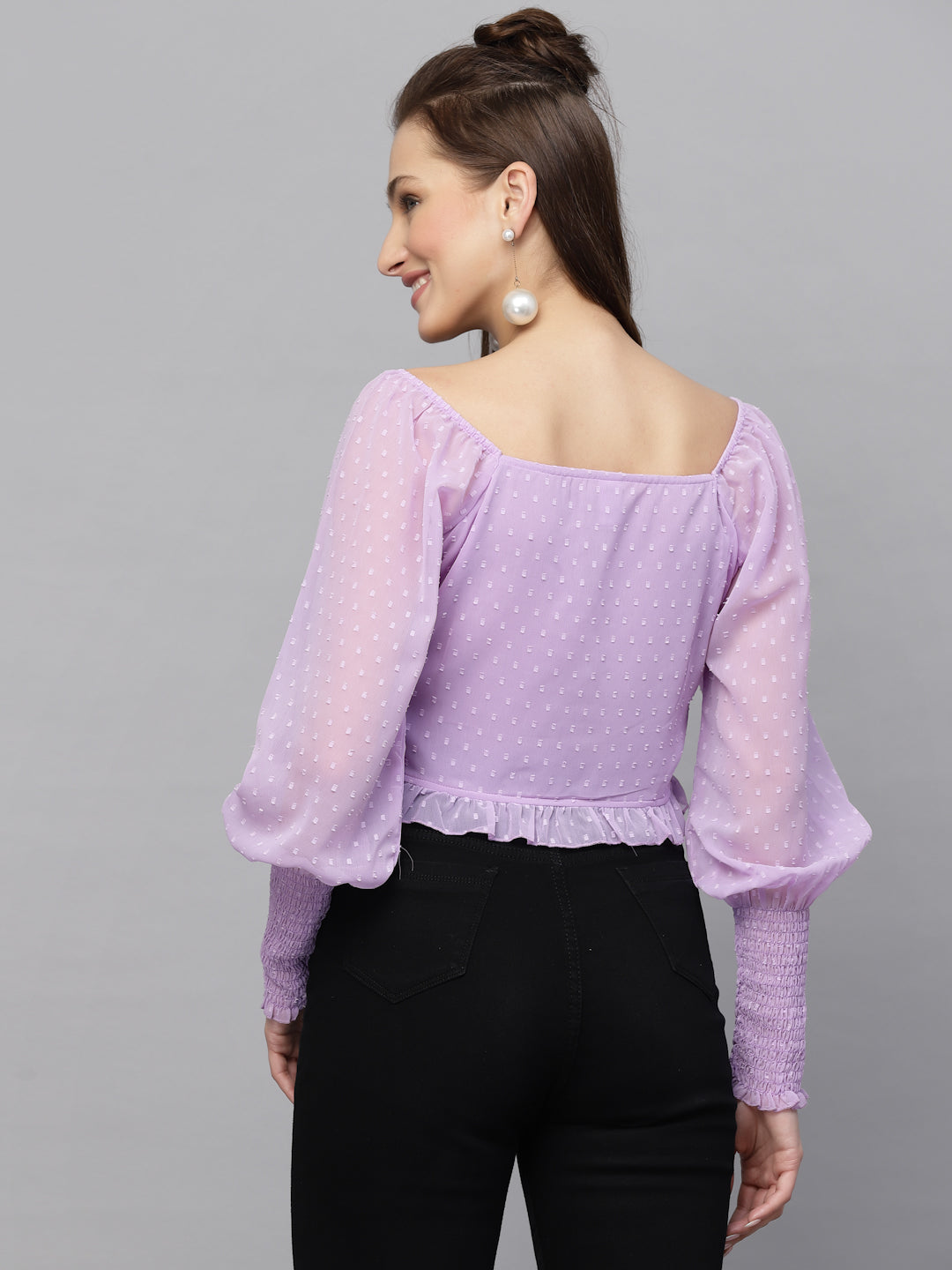 Woman wearing a purple top with long sleeves on a gray background