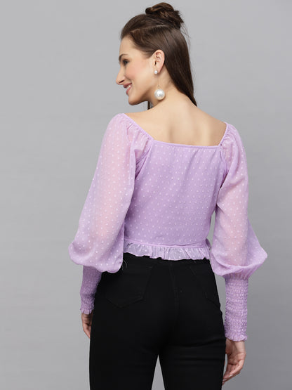 Woman wearing a purple top with long sleeves on a gray background