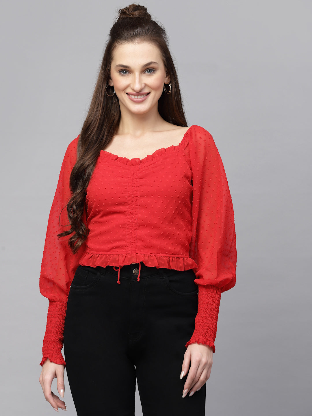 Woman wearing a red top with long sleeves on a gray background