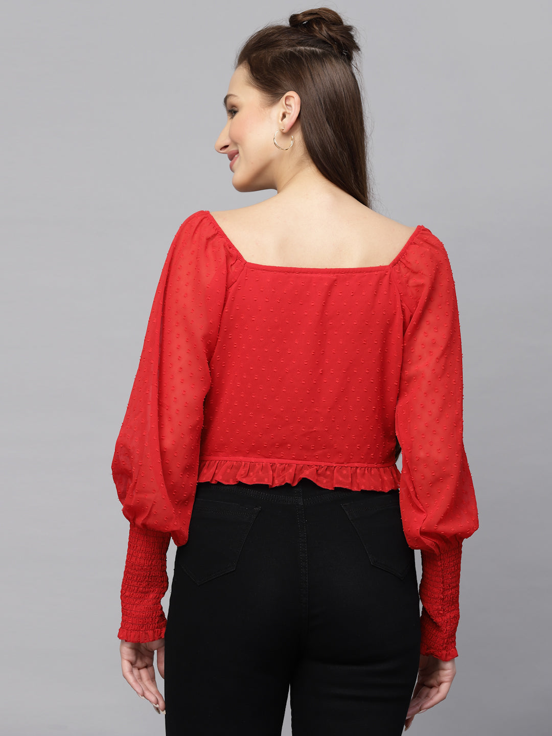 Woman wearing a red top with long sleeves on a gray background