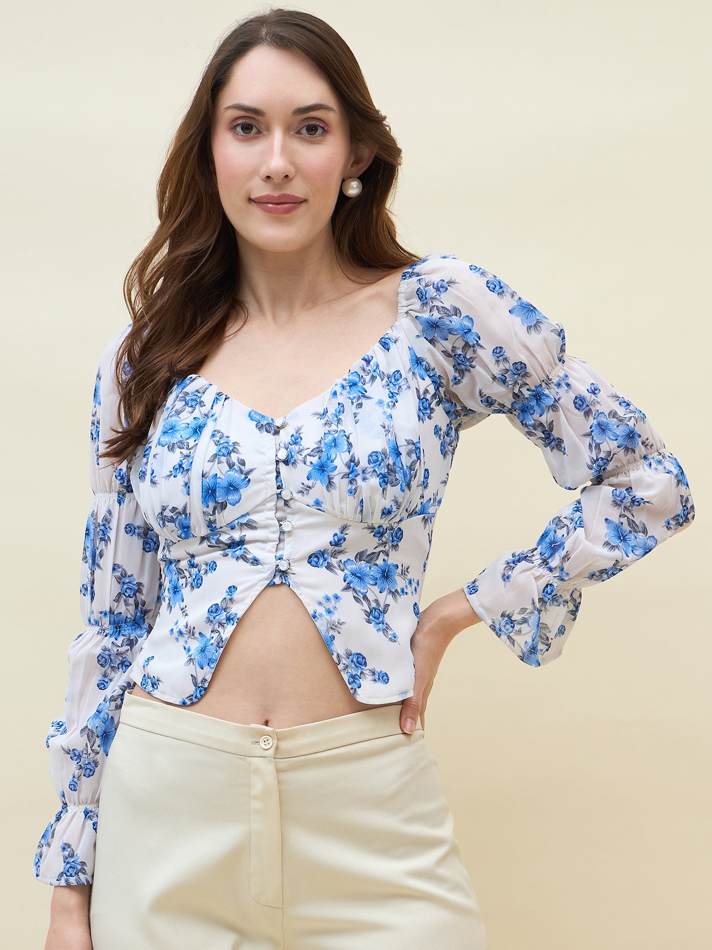 Woman wearing a blue floral top with long sleeves on a beige background