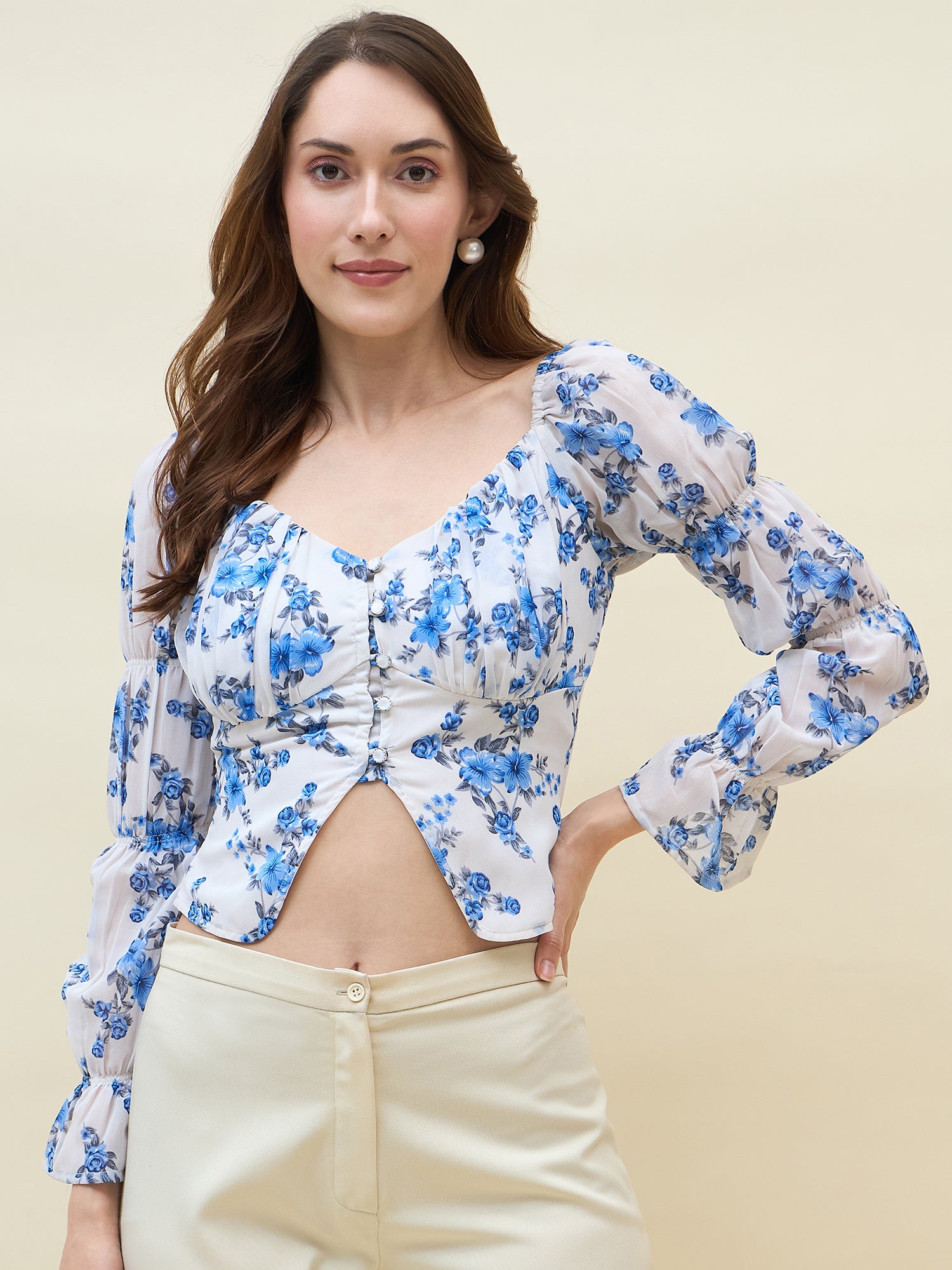 Woman wearing a blue floral top with long sleeves on a beige background