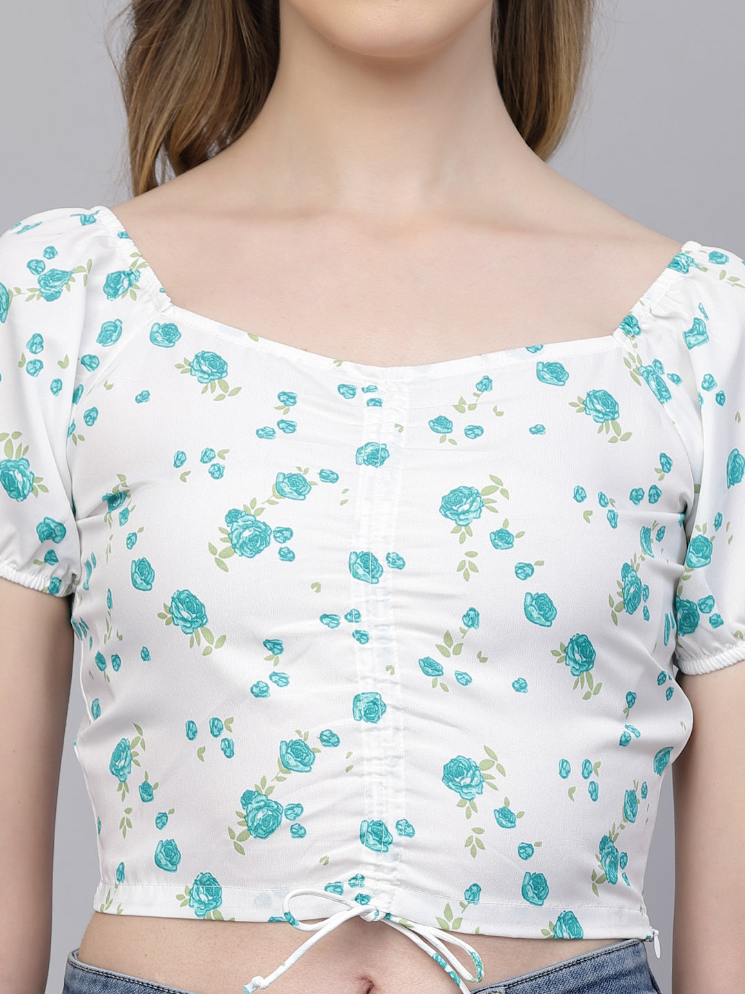 White crop top with blue floral pattern worn by a person on a gray background