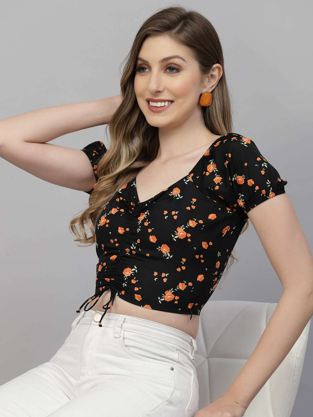 Woman wearing a black floral top with orange flowers on a gray background