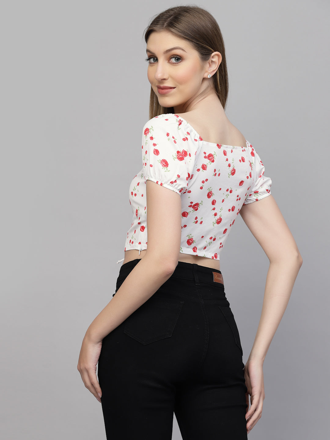 Woman wearing a white floral top with red flowers on a gray background