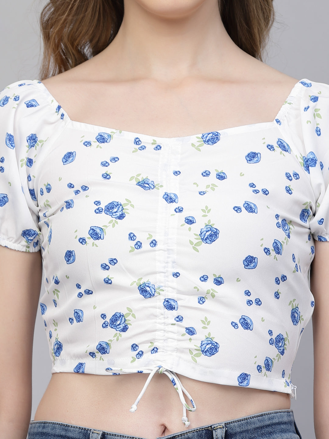 White crop top with white & blue floral pattern worn by a person on a plain background