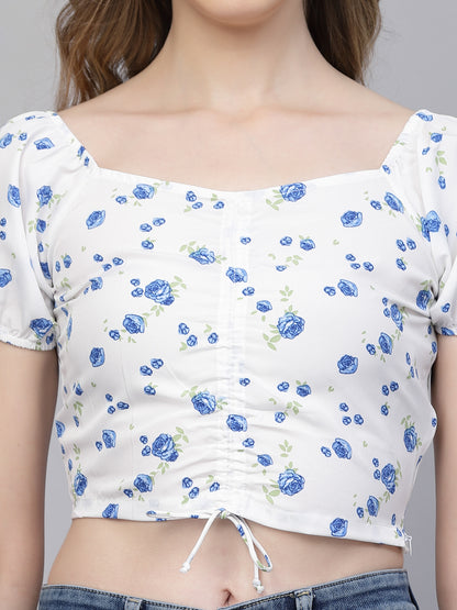 White crop top with white & blue floral pattern worn by a person on a plain background